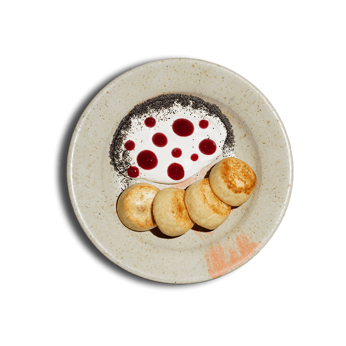 A plate of golden cottage cheese pancakes served with sour cream — a traditional Ukrainian dish from 100 rokiv tomu vpered.